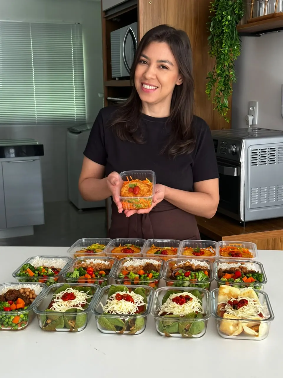 Lindeise segurando uma marmita pronta na cozinha